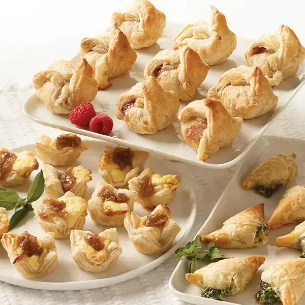 Appetizer Favorites Trio, featuring Caramelized Onion & Feta Pastry Blossoms, Brie & Raspberry en Croute, and Spanakopita.